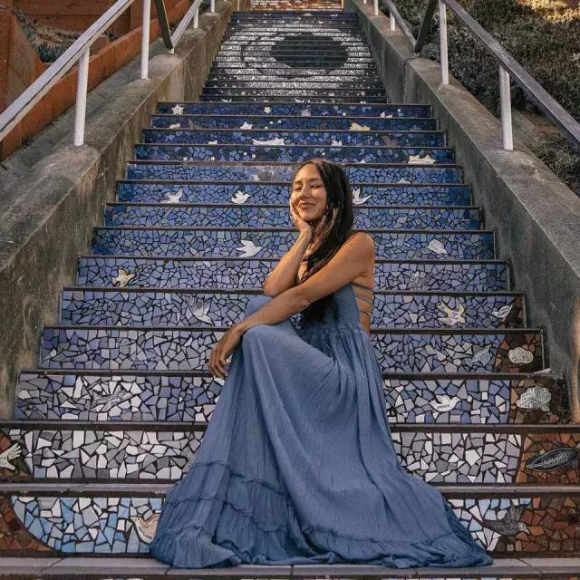 一个女人坐在贝博体彩app日落区第16大道的瓷砖楼梯上。.